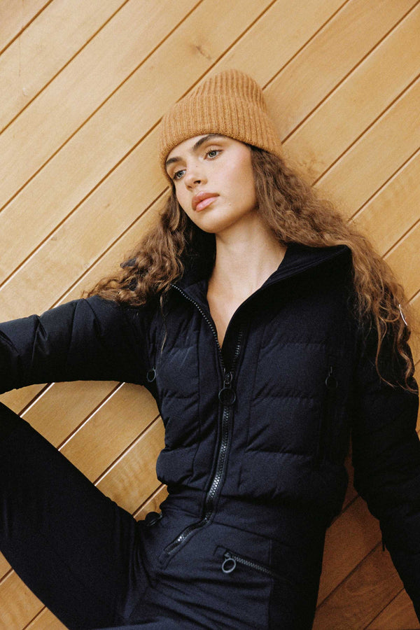 Model wearing a cinnamon rib beanie against a wooden wall