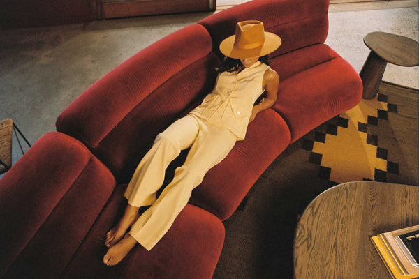 Model wearing a Desert Sun Rancher wool felt hat in a stylish setting on a red couch