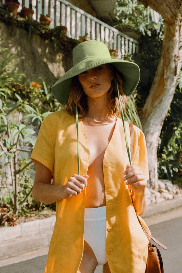 Model wearing a green Holiday Bucket hat with a yellow shirt and white bottoms, outdoors.