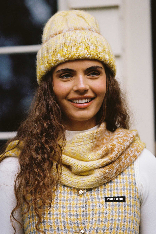 Model wearing a yellow Kai Beanie and matching scarf, with text on clothing.
