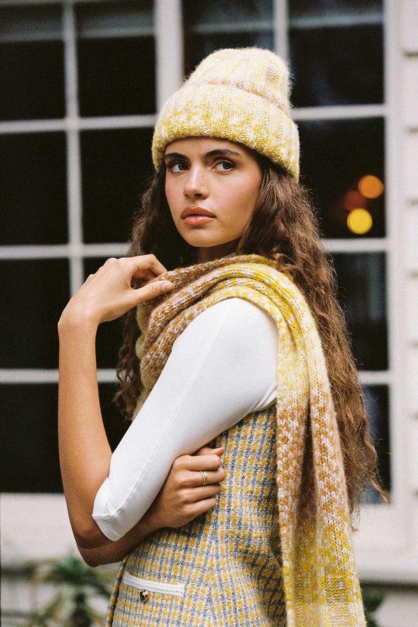 Model wearing a yellow Kai Beanie and matching scarf, with a blurred background.