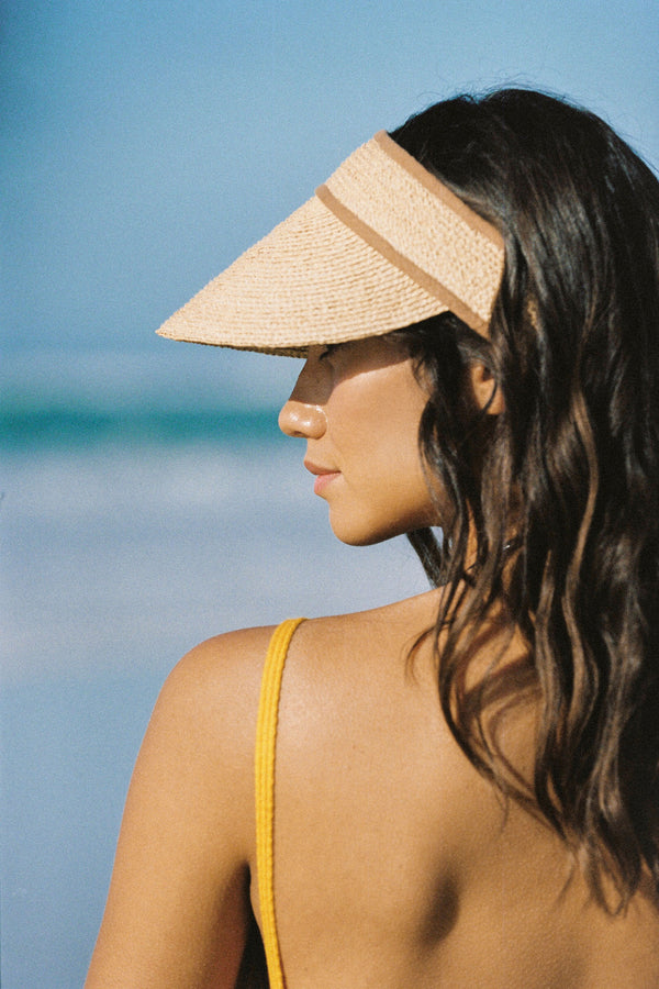 A woman wearing a natural straw linen visor at the beach, showcasing its design and fit.