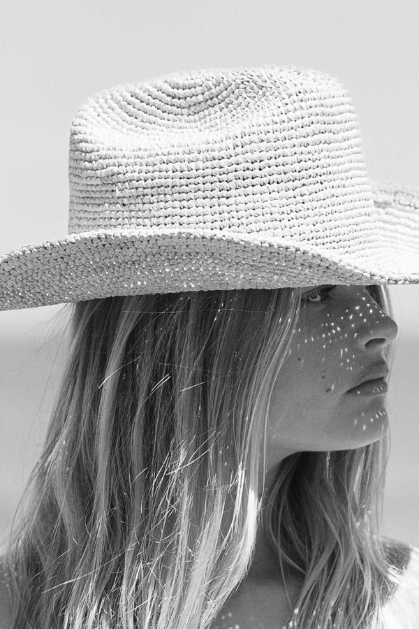 Raffia Cowboy straw hat in natural color, worn by a model with long hair, featuring a wide brim.