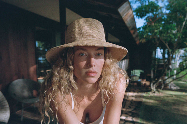 A woman wearing The Inca Bucket straw hat, showcasing its natural color and wide brim in an outdoor setting.