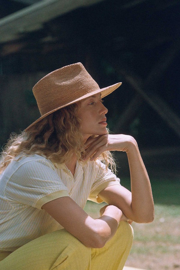 Model wearing The Inca Fedora, a natural straw fedora hat, outdoors.