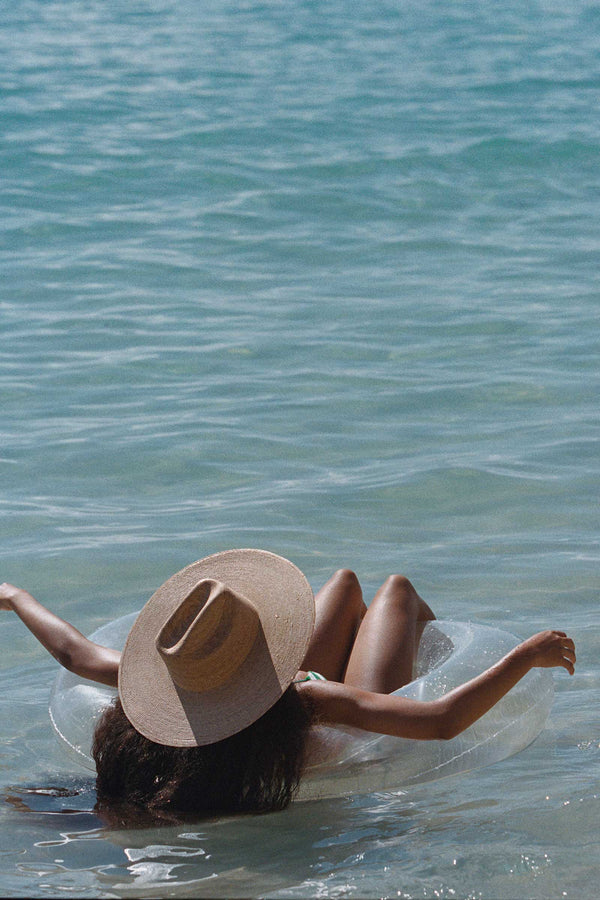 Person relaxing in water wearing a wide-brimmed straw cowboy hat