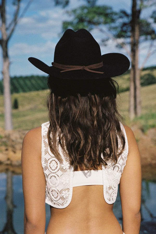 Model wearing a black wool felt Wilder Cowboy hat, with a scenic background.