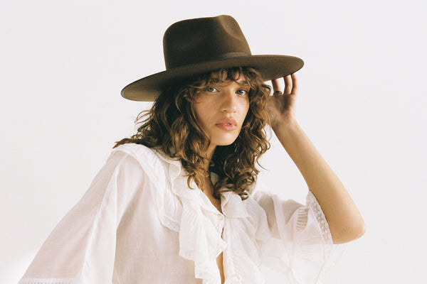 Model wearing an Espresso Rancher wool felt hat in brown, with a white blouse and curly hair.