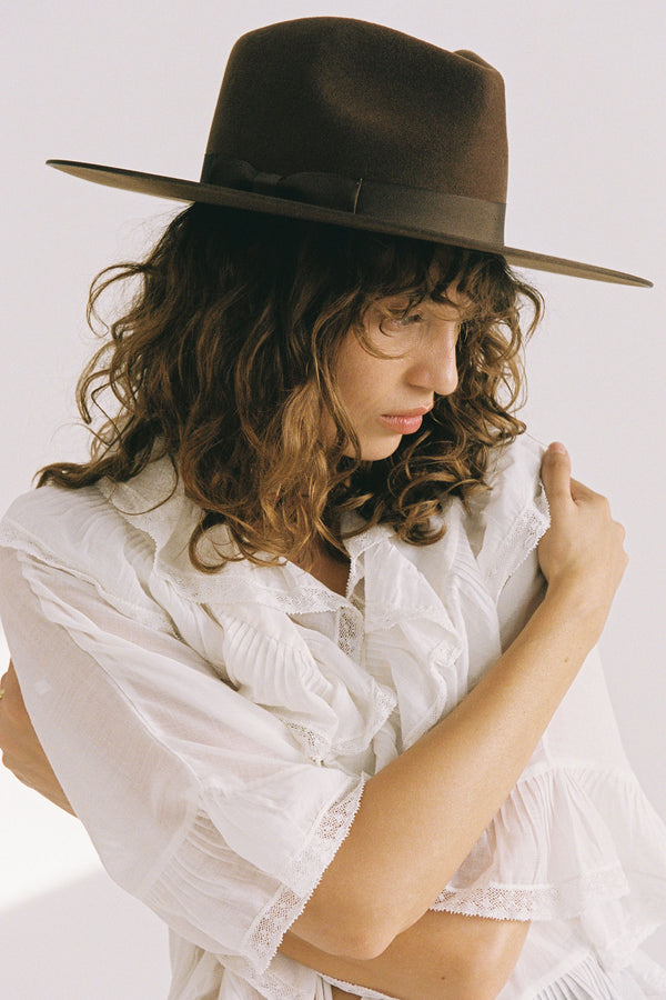 Model wearing an Espresso Rancher wool felt hat in brown, showcasing its design and style.