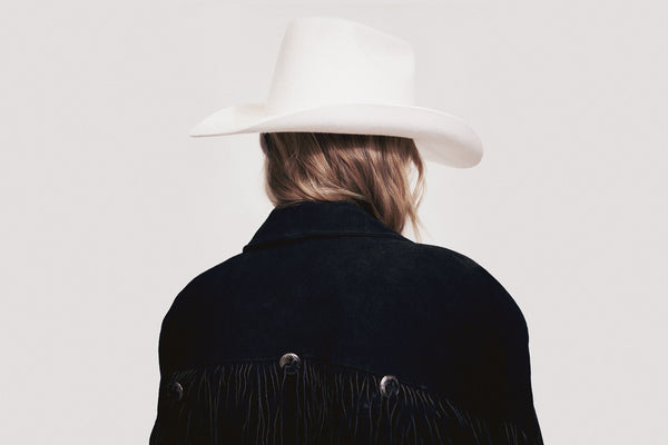 Back view of a person wearing a white Nash Western wool felt cowboy hat and a black fringed jacket