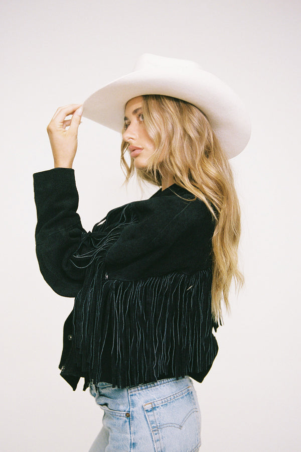 Model wearing the Nash Western wool felt cowboy hat in white, styled with a black fringed jacket.