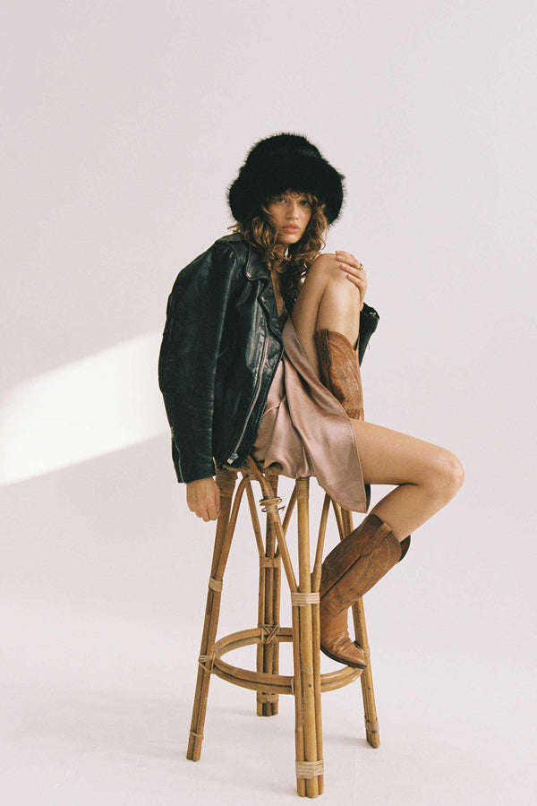 Model wearing a black faux-fur bucket hat with a leather jacket and brown boots