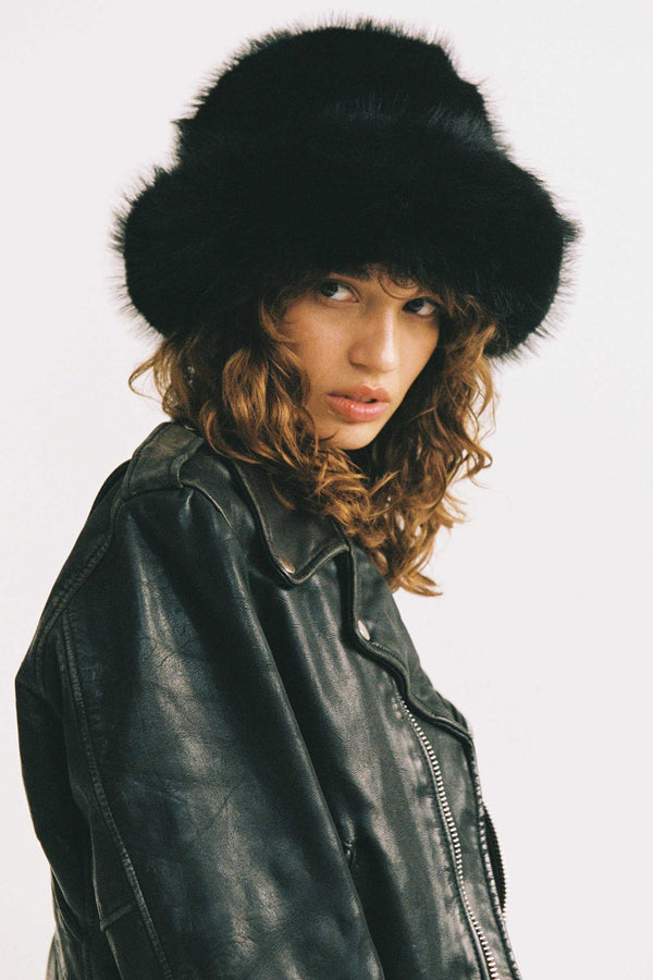 Model wearing a black faux-fur Snuggle Bucket hat with a leather jacket