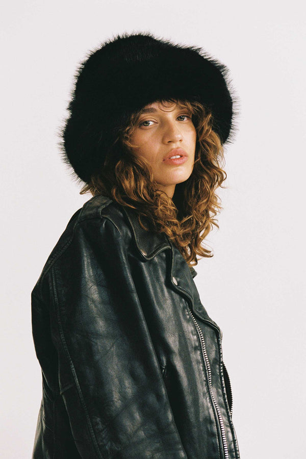 Model wearing a black faux-fur bucket hat with a leather jacket