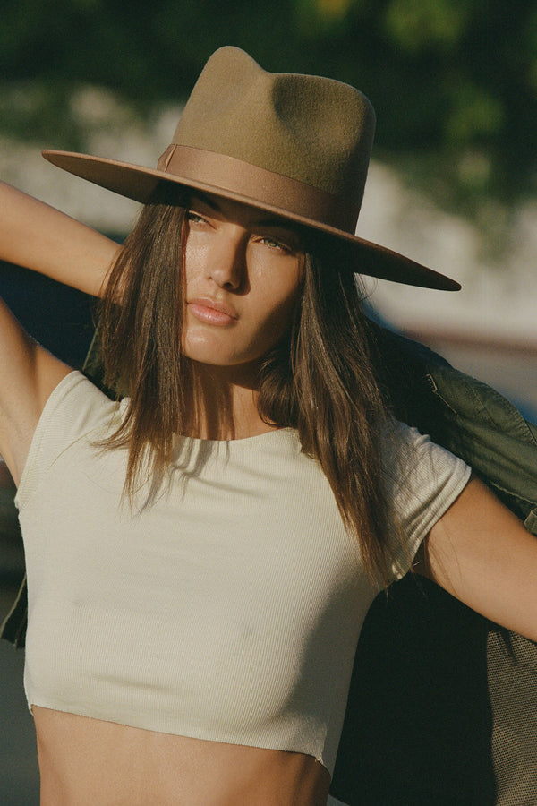 Model wearing a Teak Rancher wool felt fedora hat in brown, styled with a light top.