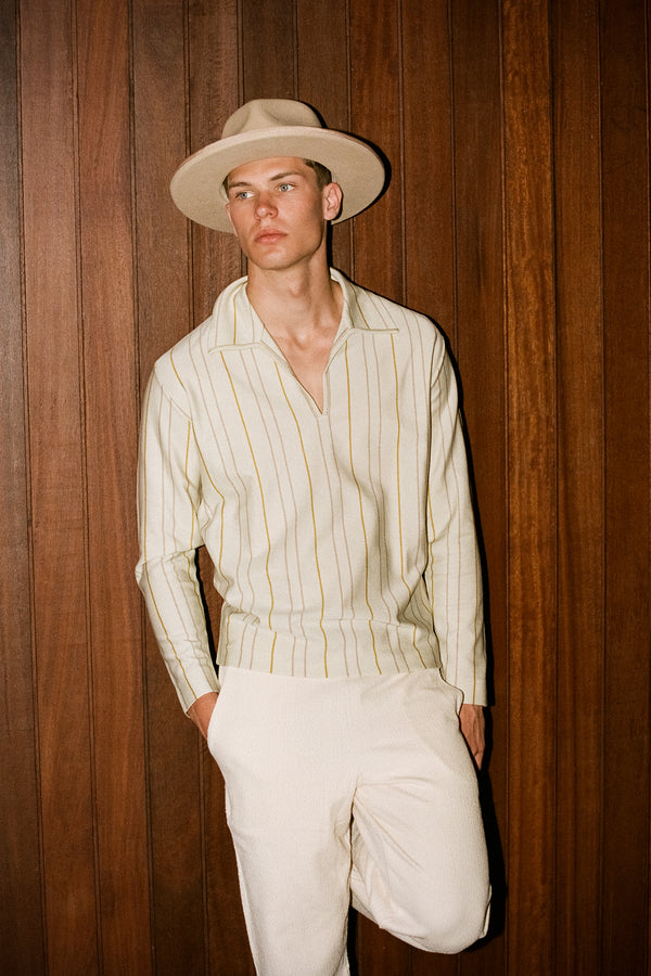 Model wearing a Pierre wool felt fedora hat in pink against a wooden backdrop.