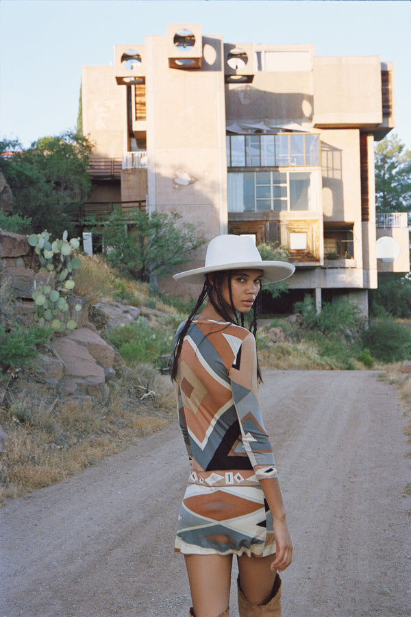 Model wearing The Melodic Fedora in a desert setting, showcasing the hat's style and fit.
