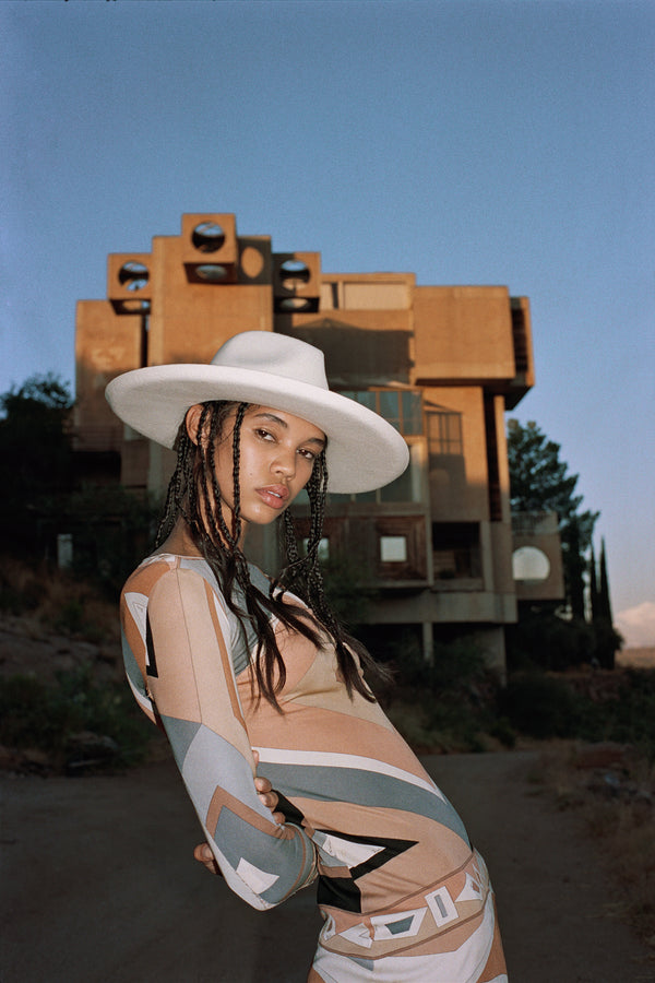 Model wearing The Melodic Fedora in a stylish outfit against a modern architectural backdrop.