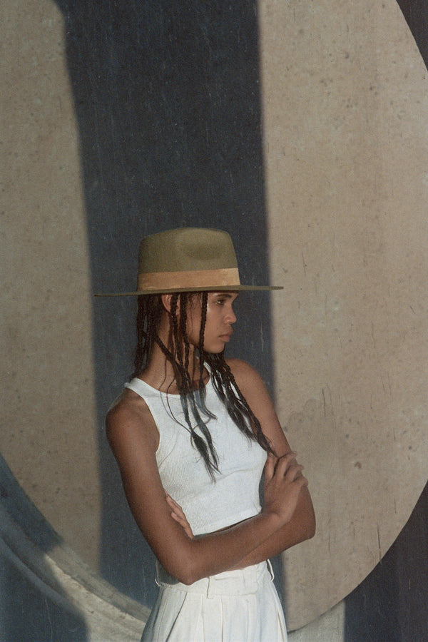 Model wearing The Mirage brown wool felt fedora hat against a textured background