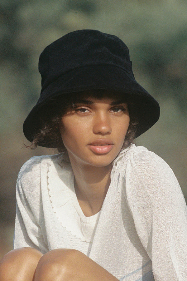 Model wearing a black cotton bucket hat, showcasing its design and fit.