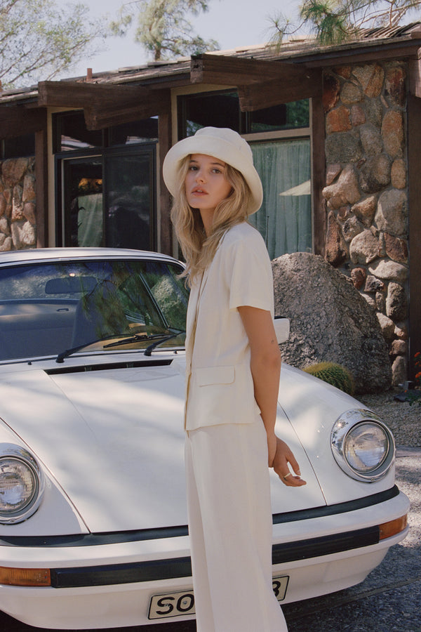 Model wearing a beige Wave Bucket Hat in front of a vintage car