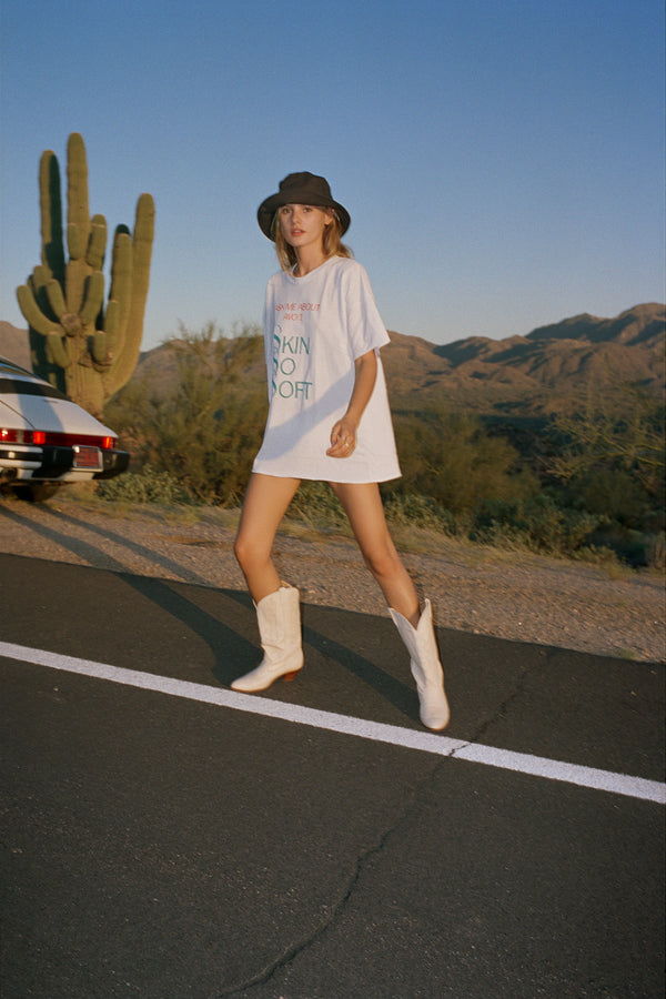 Model wearing a black Wave Bucket Hat, white shirt, and cowboy boots in a desert setting.