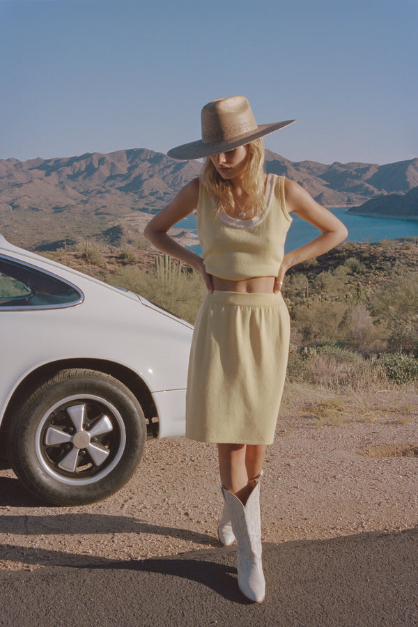 Model wearing a Western Wide Palma straw cowboy hat, standing near a white car with mountains in the background.