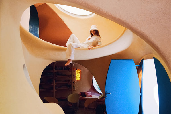 Model wearing a cream puffer bucket hat in a colorful architectural space