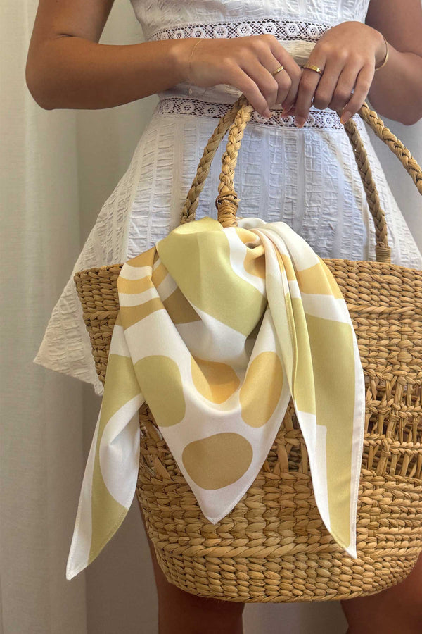Pistachio Scarf displayed on a woven bag, featuring a pastel print with circles.