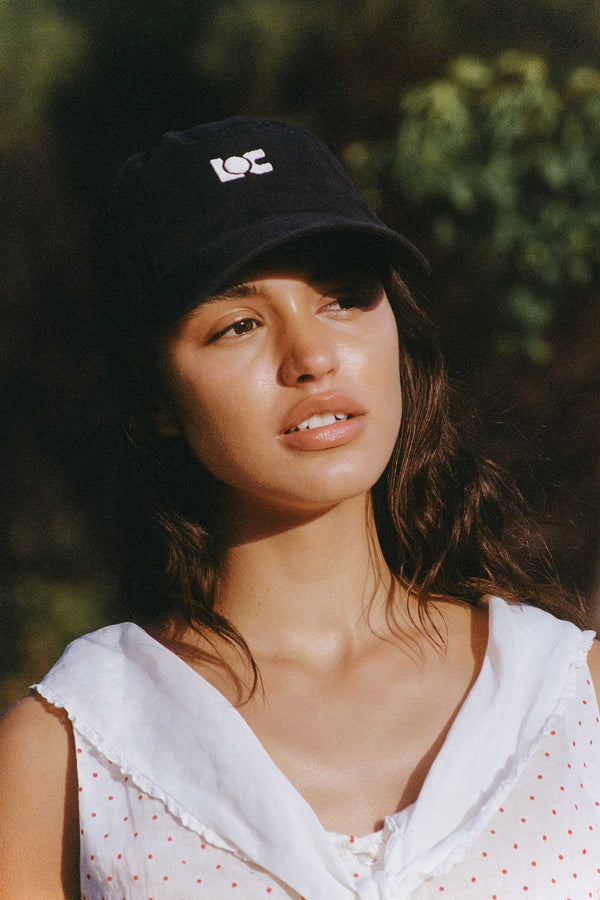 Model wearing the LOC Cap in washed black, featuring an embroidered logo.