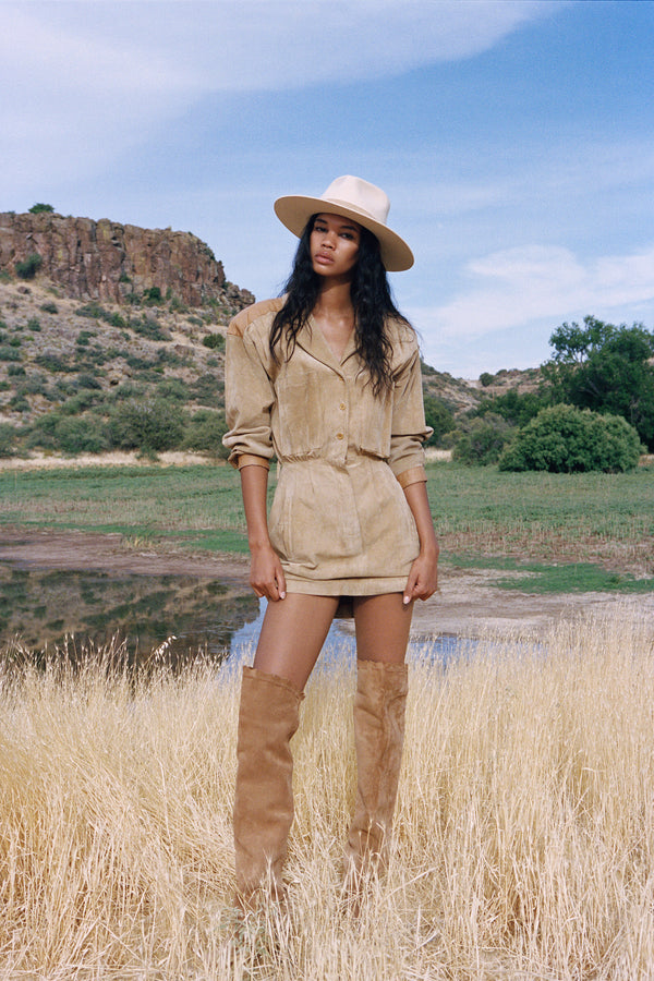 Model wearing The Mirage ivory wool felt fedora hat in a natural landscape